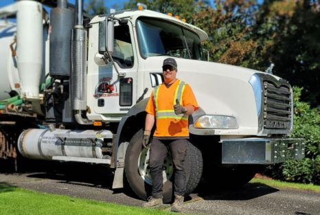 Service technician standing beside vacuum truck equipment for planned maintenance.
